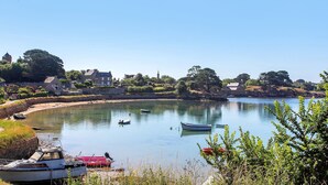 Un lago tranquilo con barcos, un muro de piedra y edificios al fondo.