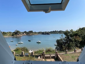 A view of a coastal area with boats on the water, a stone wall, and greenery. - Holiday Home 'Bréhat - Villa San Denn' with Sea View, Private Garden and Wi-Fi (Île-de-Bréhat)