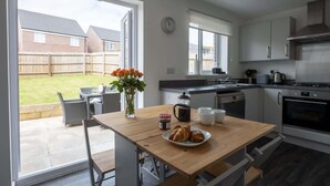 Una cucina moderna con zona pranzo, ampie finestre e vista sul giardino.