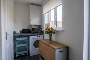 Convenient laundry room with washing machine, microwave, and storage for essentials.