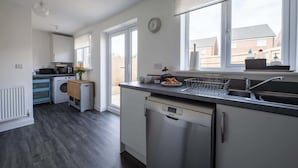 Una cucina moderna con lavastoviglie, lavello e finestra vista su zona residenziale.