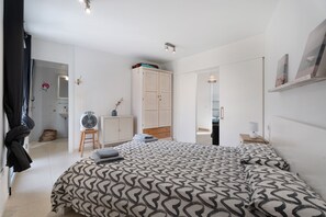 Et soveværelse med sengetæppe med mønster, et garderobeskab, et natbord med lampe og et spejl.