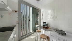 A modern kitchen with a built-in washing machine, a coffee maker, and a sliding glass door leading to a balcony. - Vacation Home 'Villa En Taro' with Sea View, Private Terrace and Wi-Fi (Güímar)