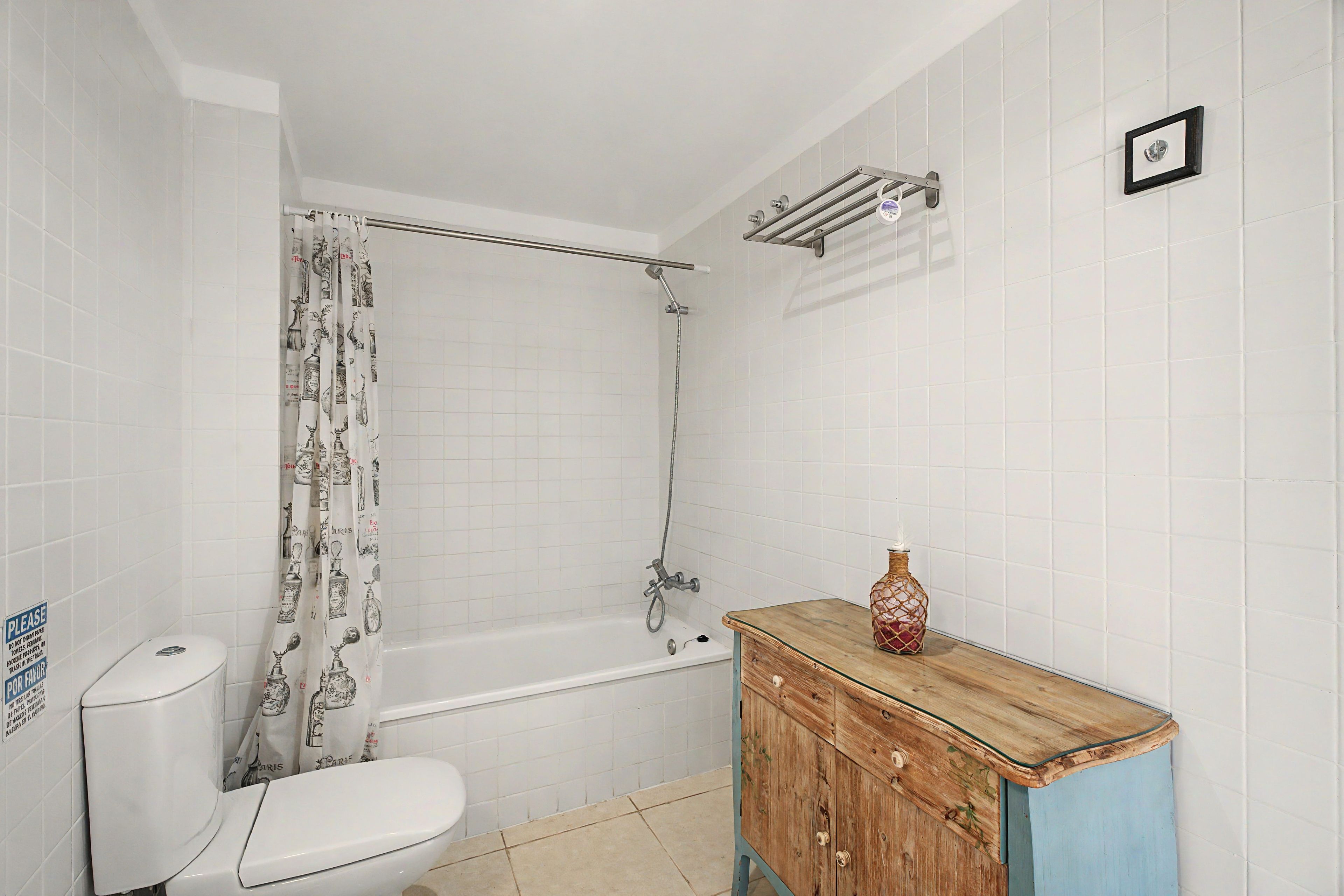 A bathroom with a toilet, shower, and wooden cabinet.