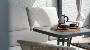 A glass table with a coffee maker and cups, a white sofa, and a wicker chair in a room with textured walls. - Vacation Home 'Villa En Taro' with Sea View, Private Terrace and Wi-Fi (Güímar)