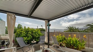 A covered patio with two lounge chairs, a table with a teapot and cups, and a view of greenery and mountains. - Vacation Home 'Villa En Taro' with Sea View, Private Terrace and Wi-Fi (Güímar)