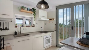 Uma cozinha moderna com uma ilha grande, forno embutido e janela com vista para um jardim.