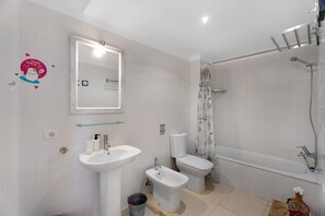 Et badeværelse med vask, bidet, toilet og badekar.