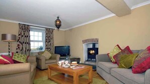 Una sala de estar con dos sofás, una mesa de centro, un televisor y una chimenea.