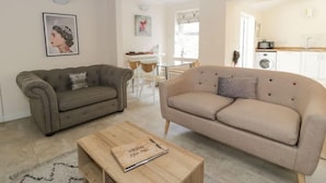 A living room with two sofas, a wooden coffee table, and a dining area with a table and chairs. - Pet-Friendly Stay Near Ruthin Castle with Parking (Ruthin)
