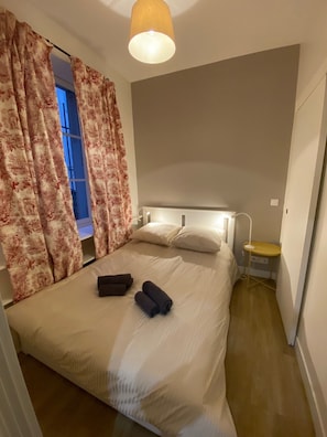 A bedroom with a bed, curtains, a bedside table, and a lamp.