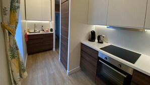 A modern kitchen with a built-in oven, a sink, and a countertop with a kettle.