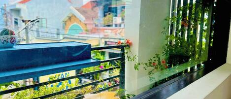 Uma varanda com vista para edifícios, um corrimão e uma janela com uma planta.