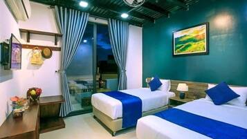 A hotel room with two beds, a desk, and a window with curtains.