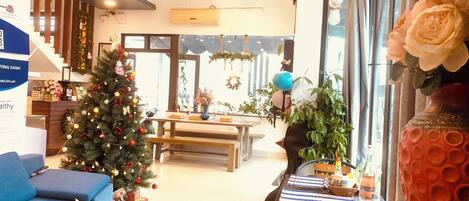 A spacious living area with a Christmas tree, a blue sofa, a coffee table, and a large window with a view.