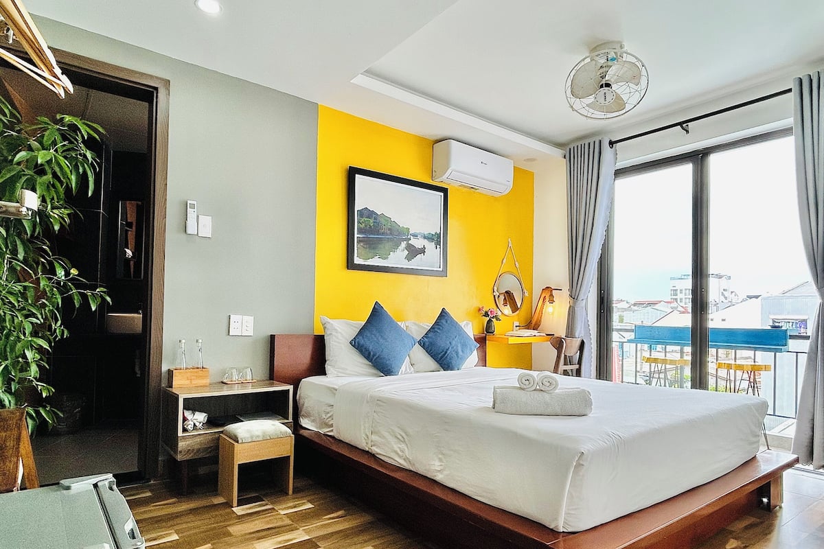 A hotel room with a bed, bedside table, and a view of the city.