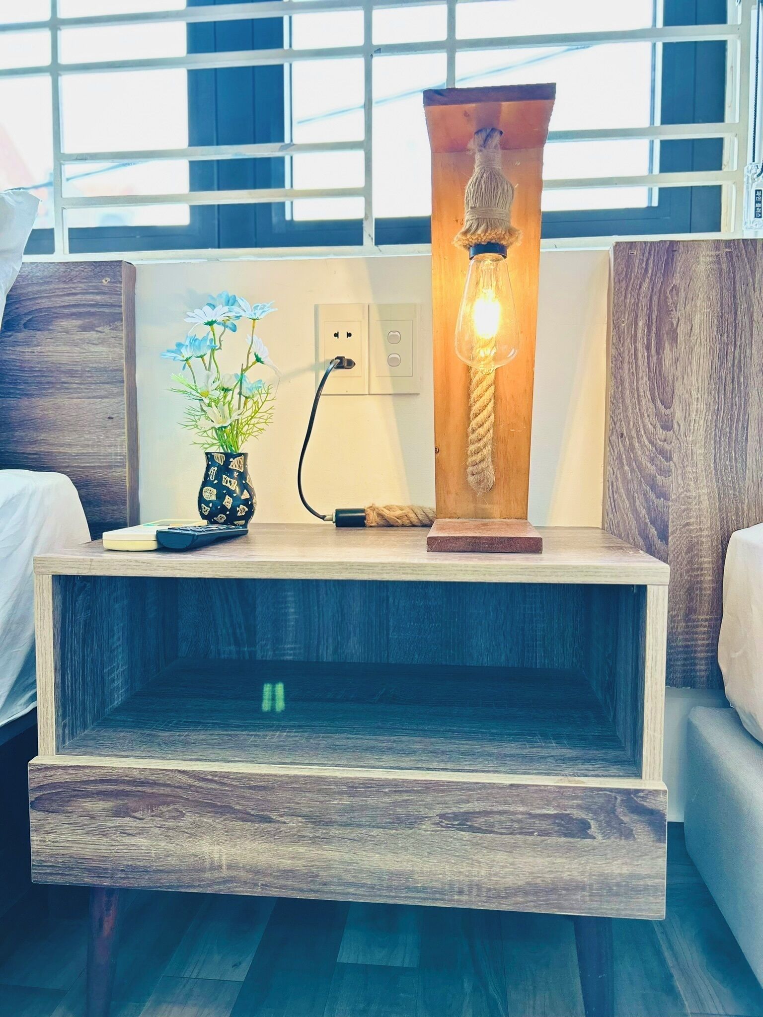 Un soggiorno moderno con un tavolino in legno, un vaso con fiori, una lampada e una presa elettrica.