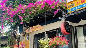 A hotel entrance with a wooden sign, a bench, and hanging flower baskets. - May's House Hoi An Ancient Town Center (Da Nang)