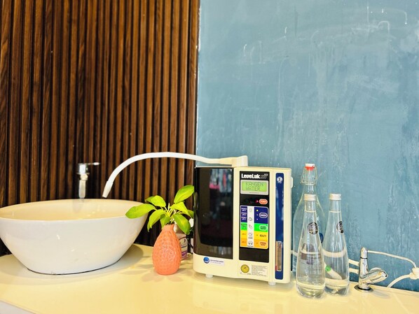 Casa de banho com lavatório branco, sistema de filtragem de água e duas garrafas transparentes.