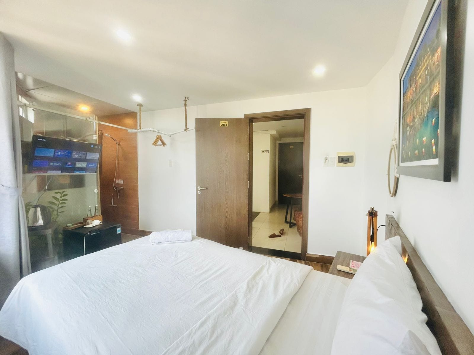 A hotel room with a bed, a TV, a mirror, and a door leading to a bathroom.