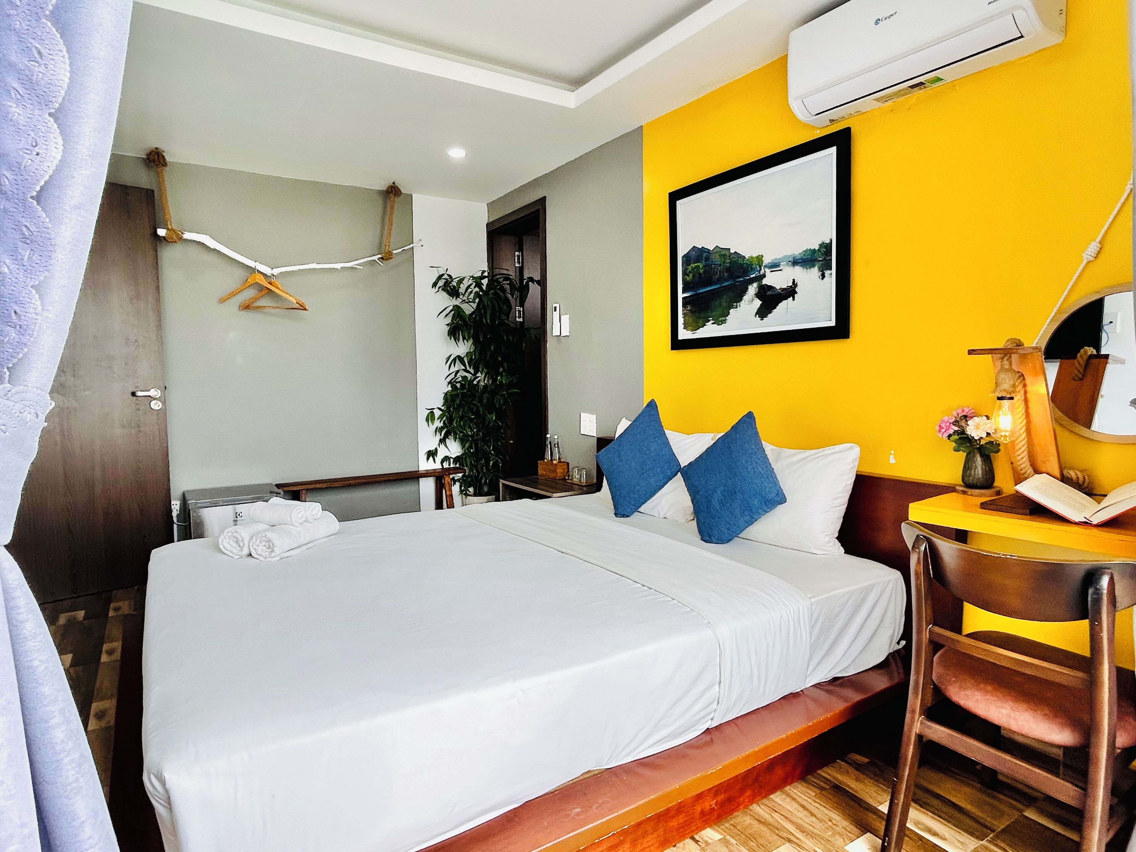 A hotel room with a bed, a desk, a chair, a mirror, and a window.