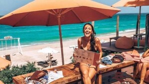 A beachside lounge with wooden tables, large umbrellas, and a view of the ocean. - May's House Hoi An Ancient Town Center (Da Nang)