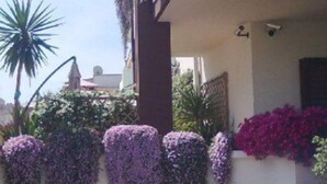 A building with a balcony adorned with purple flowering vines and a red flower bed. - Apartment In A Hotel 'Bnb Sottosopra Intero 8 Pax' with Sea View, Shared Terrace and Wi-Fi (Gallipoli)