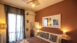 A bedroom with a bed, two wall-mounted lamps, a ceiling fan, and a window with curtains. - Apartment In A Hotel 'Bnb Sottosopra Intero 8 Pax' with Sea View, Shared Terrace and Wi-Fi (Gallipoli)