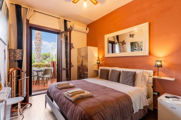 Une chambre d’hôtel équipée d’un lit, d’un bureau, d’une chaise, d’un réfrigérateur et offrant une vue sur l’extérieur.