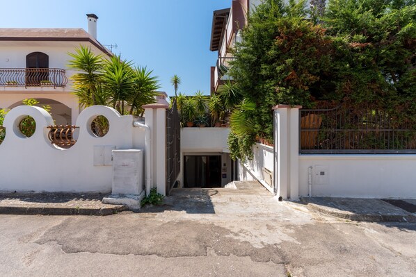 A gated entrance with a white wall, a metal gate, and a small door.