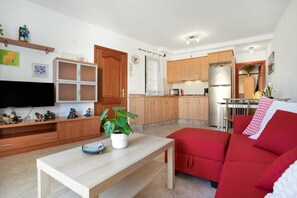 Un salon moderne avec un canapé rouge, une table basse en bois et un téléviseur.