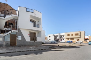 Un immeuble résidentiel à plusieurs étages, doté d’un escalier, de balcons et d’une entrée sécurisée par un portail.