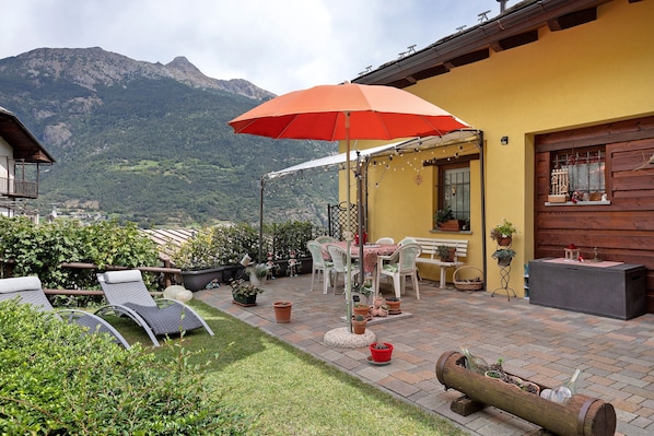 A patio with outdoor furniture, a dining table, and potted plants.