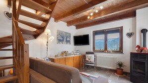Eine Holztreppe, ein Sofa, ein Fernseher, ein Fenster und ein Kamin.