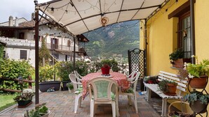 Eine Terrasse mit Tisch, Stühlen, Kübelpflanzen und einer Bank.