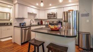 A modern kitchen with white cabinets, stainless steel appliances, and a central island with stools.