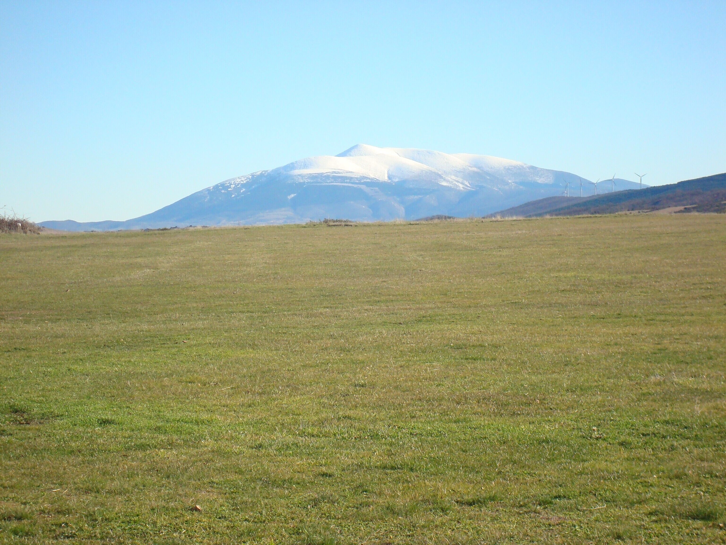 Un campo extenso cubierto de hierba con una montaña al fondo.