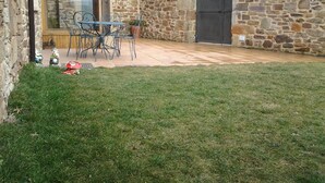 Edificio de piedra con un patio, una mesa y sillas.
