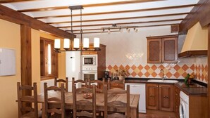 Una cocina con armarios de madera, una mesa de comedor con sillas, un microondas y una lavadora.