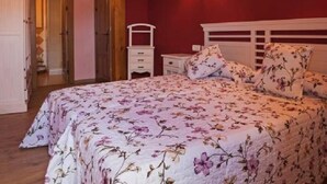 Un dormitorio con colcha estampada, cabecera de madera, mesita de noche y lámpara de pared.