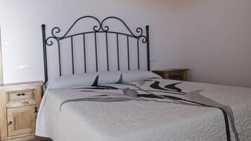 A bed with a metal frame, a wooden nightstand, and a wall-mounted light fixture.