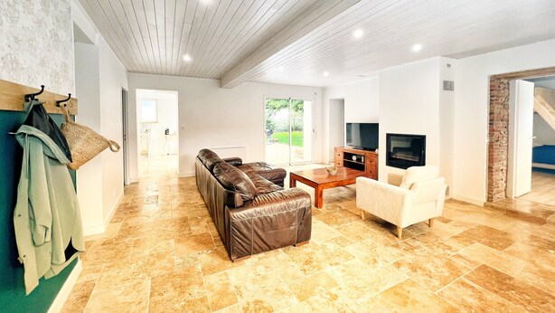 A spacious living area with a leather sofa, a wooden coffee table, a television, and a fireplace.