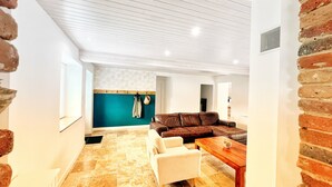 A modern living room with a brown leather sofa, a white armchair, and a wooden coffee table.