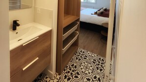 A bathroom with a sink, mirror, and wooden shelving unit.