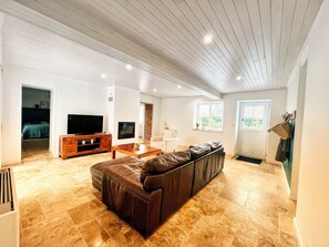 A spacious living room with a large brown leather sofa, a wooden coffee table, a flat-screen TV, and a stone fireplace. - Holiday Home 'Maison Proche Sables D'Olonne 8p' with Private Terrace and Air Conditioning (Sainte-Foy)