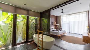 Une salle de bain moderne avec une baignoire sur pieds, une échelle en bois et une douche en verre agrémentée de plantes.