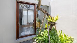 Une maison moderne dotée d’une porte vitrée donnant sur un patio aménagé avec des meubles et des plantes.