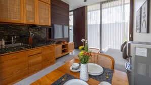 Une cuisine moderne avec des meubles en bois, un plan de travail en marbre et un coin repas avec une table dressée pour deux personnes.