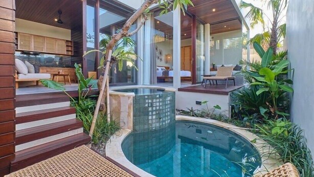 Une maison moderne dotée d’une piscine, d’une terrasse en bois et d’une végétation luxuriante.