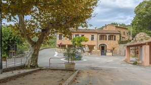 Un bâtiment en pierre, avec un rond-point, un arbre et un panneau indiquant un restaurant.